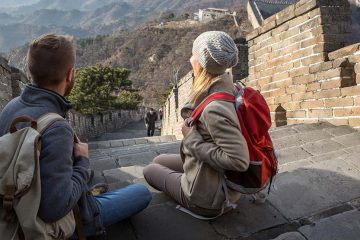 A man and woman sitting on steps of Great Wall of China.
