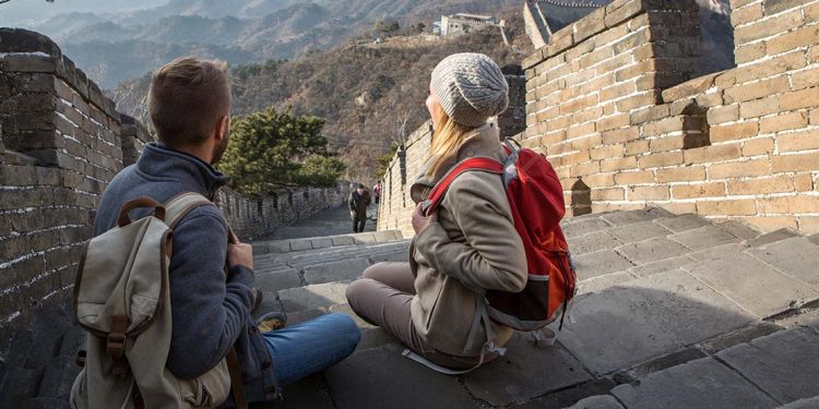 A man and woman sitting on steps of Great Wall of China.