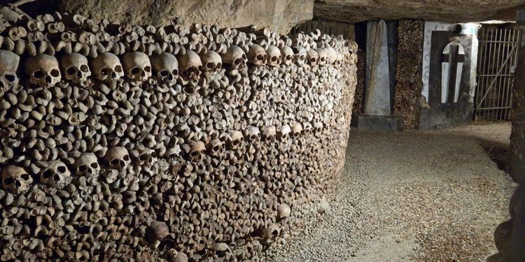 Underground tunnel with skulls and other bones stacked up the wall.