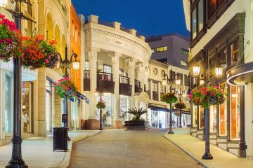 Cobblestone street with white sidewalks and metal streetlamps. Shop fronts are all white stucco.