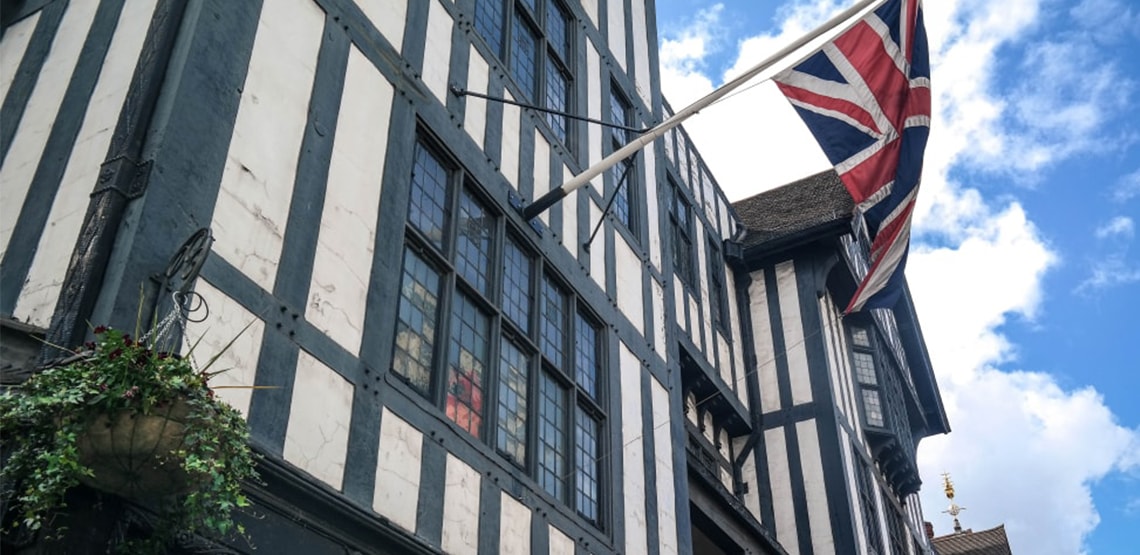 The Union Jack flag hanging off front of a shop, white with black stripes horizontal and vertical.