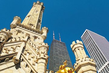 Old stone tower rises up beside skyscrapers.