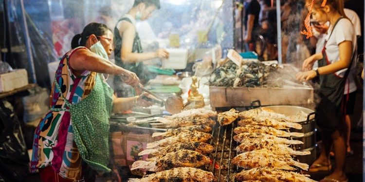Street vendor cooks fish on a grill