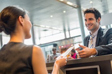 Smiling airline employee hands someone their passport over a counter