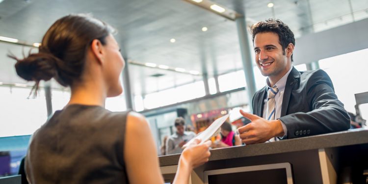 Smiling airline employee hands someone their passport over a counter