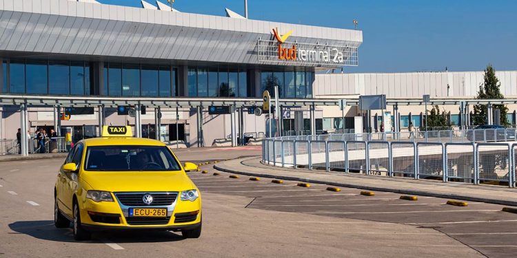 A yellow taxi drives away from the terminal.