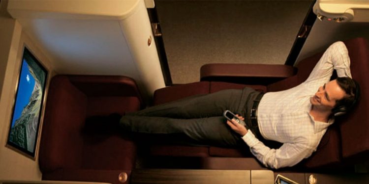 Man lounges in a chair in a private pod as he watches TV.