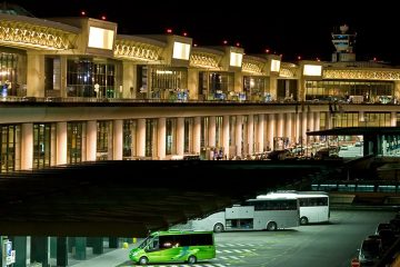 Outside the Milan Malpensa Airport, buses and shuttles parked outside waiting for passengers to disembark.