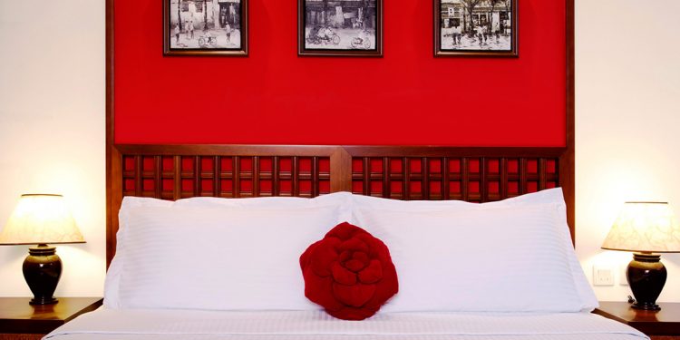 Red wall and white bed in the Butterfly on Wellington hotel.