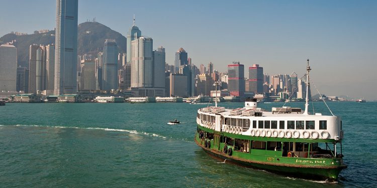 A green and white ferry heads toward the skyscrapers on Victoria Harbour.