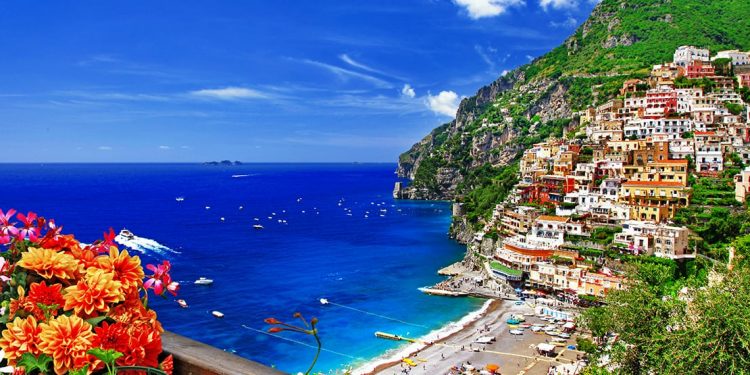 A view of colorful dwellings, the beach, and the ocean beyond in Positano, Italy.