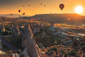 Hot air balloons over Cappadocia, rock formations rising into the sky.