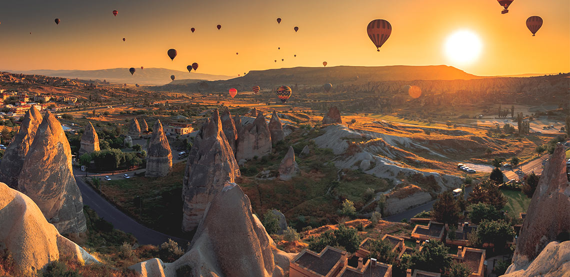 Hot air balloons over Cappadocia, rock formations rising into the sky.