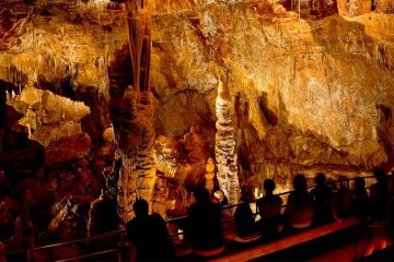 People sitting in front of lit up cave walls