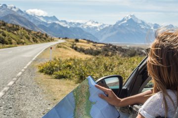 a girl reads a map while driving down the road in New Zealand