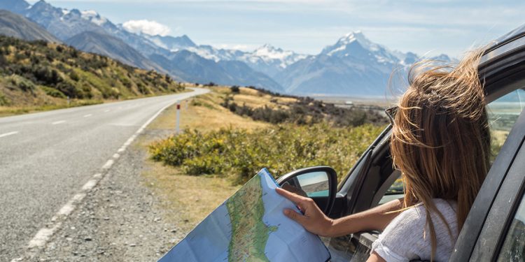 a girl reads a map while driving down the road in New Zealand