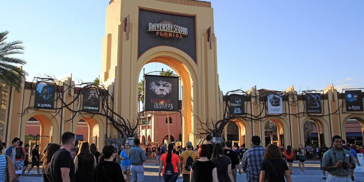 Entrance to Universal Studios with people milling about and vines on entryway.