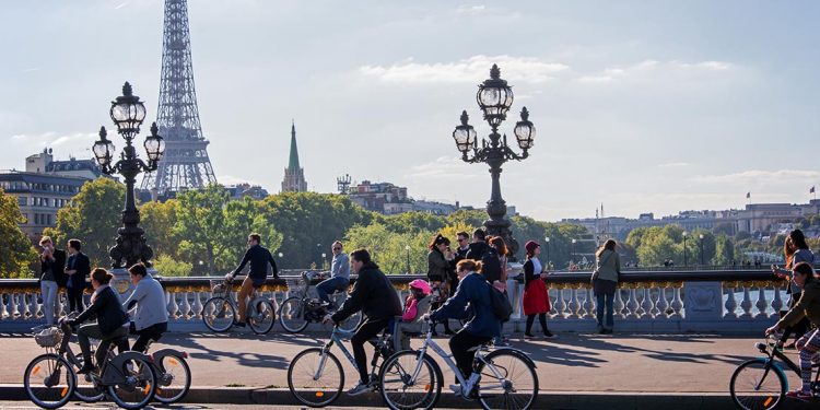 Cyclists riding along bridge with Eiffel Tower in background