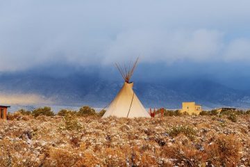Teepee erected in a field surrounded by sage bushes and snow in Taos, New Mexico