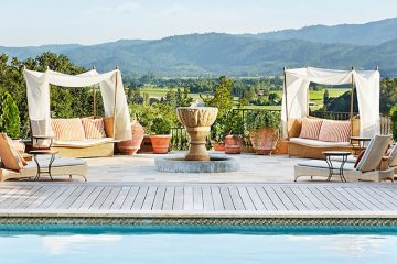 Pool with lounge chairs alongside and green rolling hills in background.