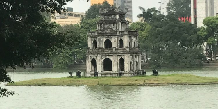 Stone building on small island in middle of lake.