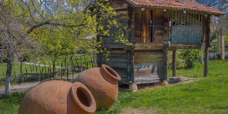 Ceramic wine vessels beside wooden shack.