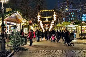 Christmas market with lights above pathway and small boots on either side.