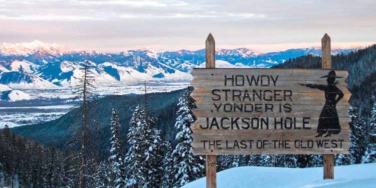 Sign reading "Howdy stranger, yonder is Jackson Hole, the last of the old west" on top of the mountain.