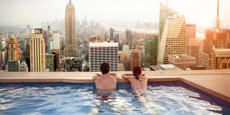 Couple looking out over city from rooftop pool.