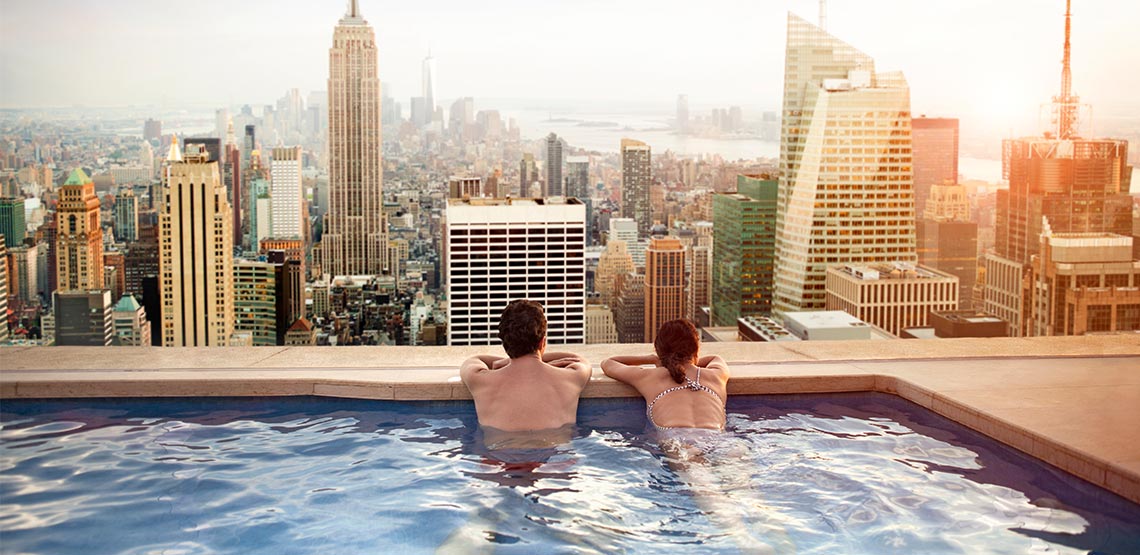 Couple looking out over city from rooftop pool.