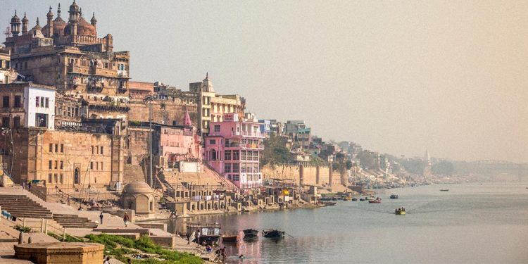 Cityscape of Varanasi with Ganges River in foreground.