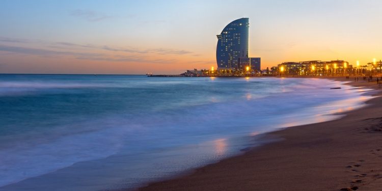 The beach of Barcelona with a modern skyscraper at sunset