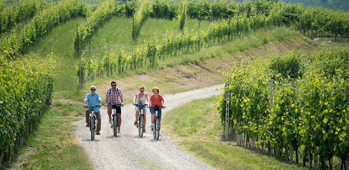 Four people on bikes riding on gravel path in Piedmont, Italy