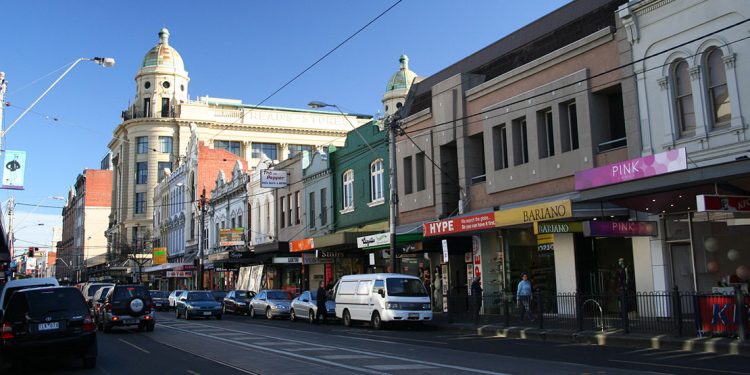 Street with cars parked along side and shops