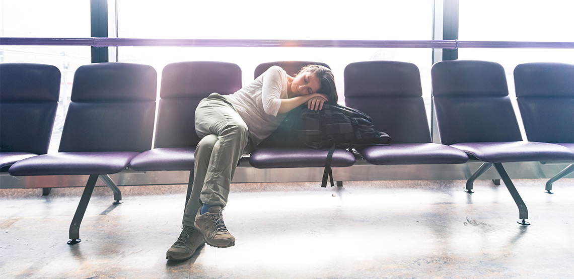 Woman sleeping on backpack in airport