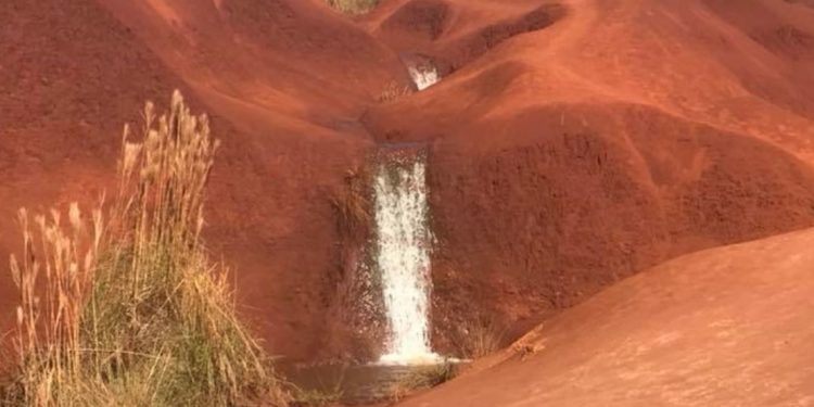 Waterfall cascades down red rock