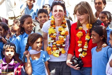 Tourists wearing flowers garlands on their necks stand among a group of school girls in India