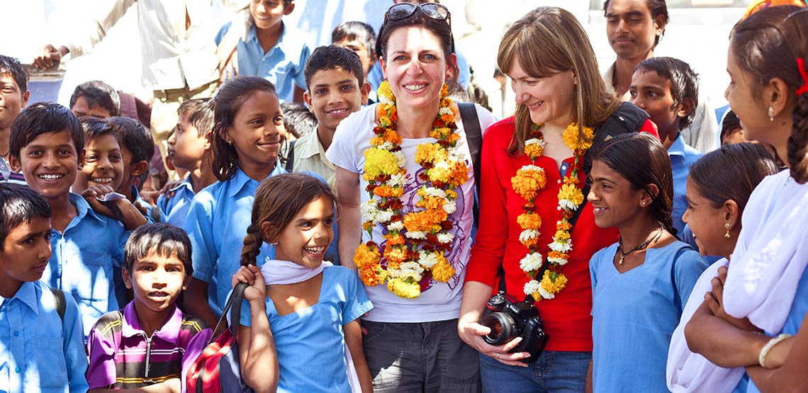 Tourists wearing flowers garlands on their necks stand among a group of school girls in India