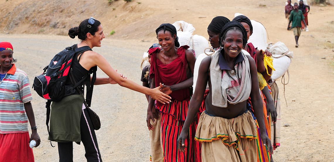 A tourist in Ethiopia greets local villagers with a culturally correct handshake