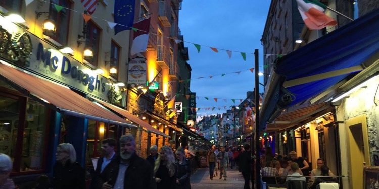 People walking down street lined with pubs in Galway