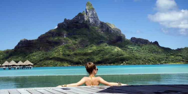 woman in infinity pool of a luxury vacation resort in the lagoon and looking on the Otemanu mountain on Bora Bora