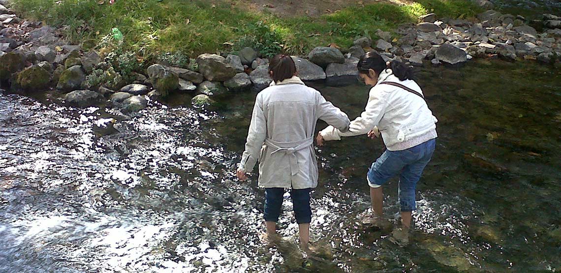 Two girls wading in river.
