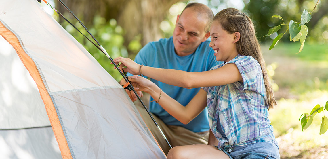 Father and daughter setting up tent.