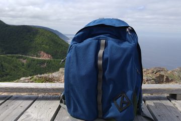 Backpack sitting on boardwalk with Cabot Trail in background