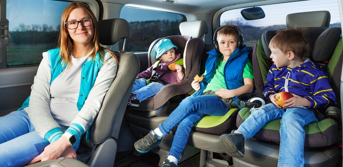 Portrait of mother and three boys sitting in a car