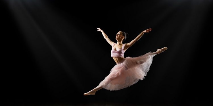 Young ballerina leaping against a black backdrop