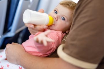 Baby girl drinking a bottle of milk on an airplane