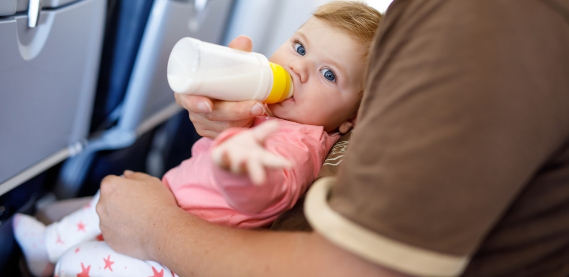 Baby girl drinking a bottle of milk on an airplane