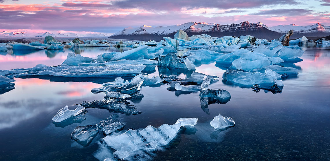 Ice and icebergs floating in water with mountains in background