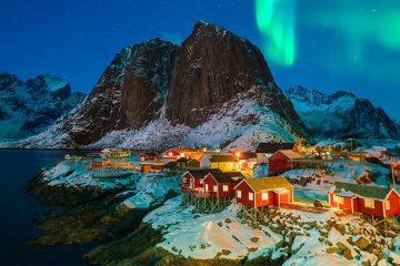 Small town with mountains in background and Northern Lights in sky